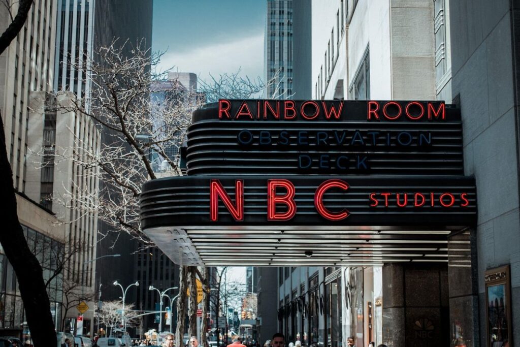 The entrance to NBC Studios in New York City, with tall buildings and pedestrians in the background