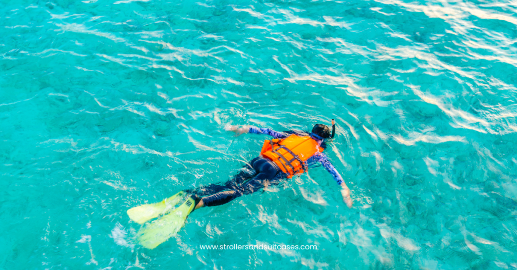 Snorkeler in a life vest exploring bright turquoise water—an inviting view of Kona’s peaceful snorkeling spots for families.